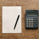 Calculadora, papel em branco, caneta e carimbo sobre mesa de madeira