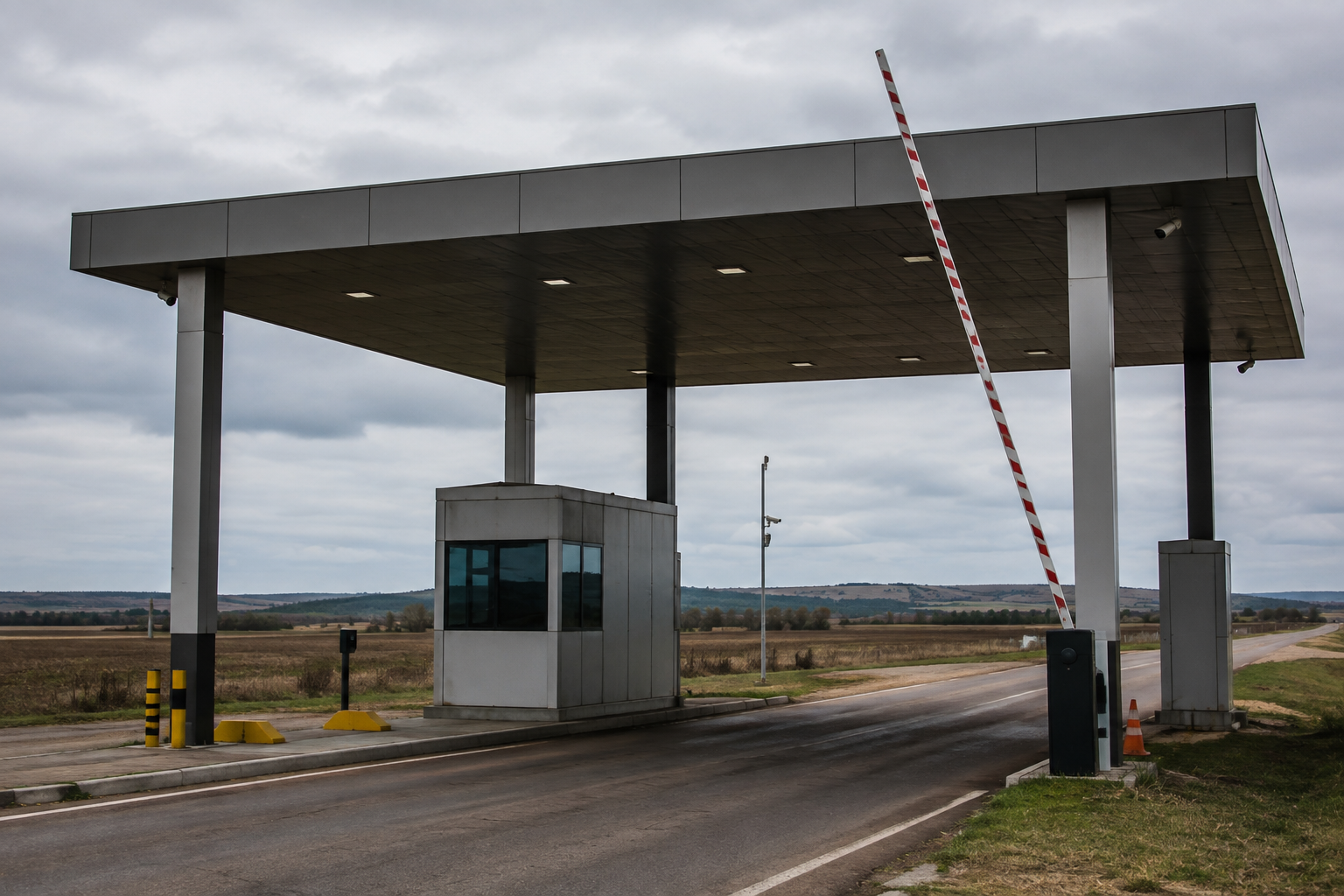 Leilão da receita federal no rio grande do sul: posto de fiscalização aduaneira em rodovia de fronteira, com cancela erguida e campo aberto ao fundo