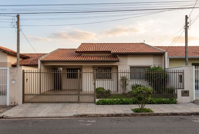 Fachada de casa residencial de um andar com portão e jardim